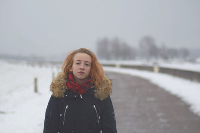 Portrait of woman standing on road during snowfall