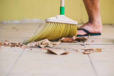 Low section of man cleaning floor with broom