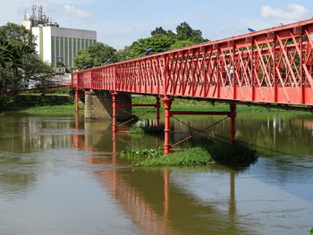 Red bridge over river against sky