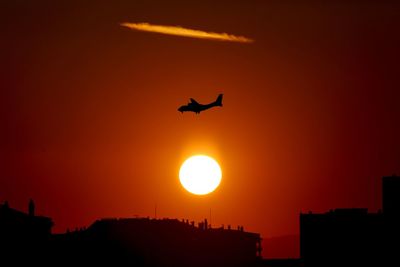 Low angle view of silhouette airplane against sky during sunset