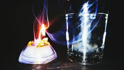 Close-up of lit candle over black background