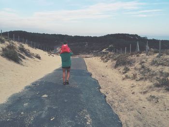 Rear view of man walking on footpath