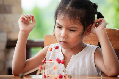 Cute girl making molecule model on wooden table in porch