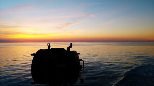 Silhouette people on sea against sky during sunset