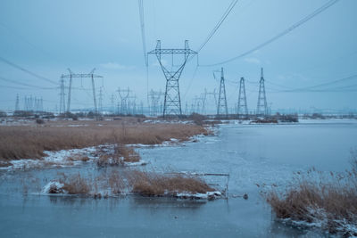 Scenic view of electricity pylon against sky during winter