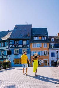 Rear view of people walking on building against sky