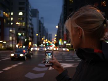 Close-up of woman using smart phone on street at night