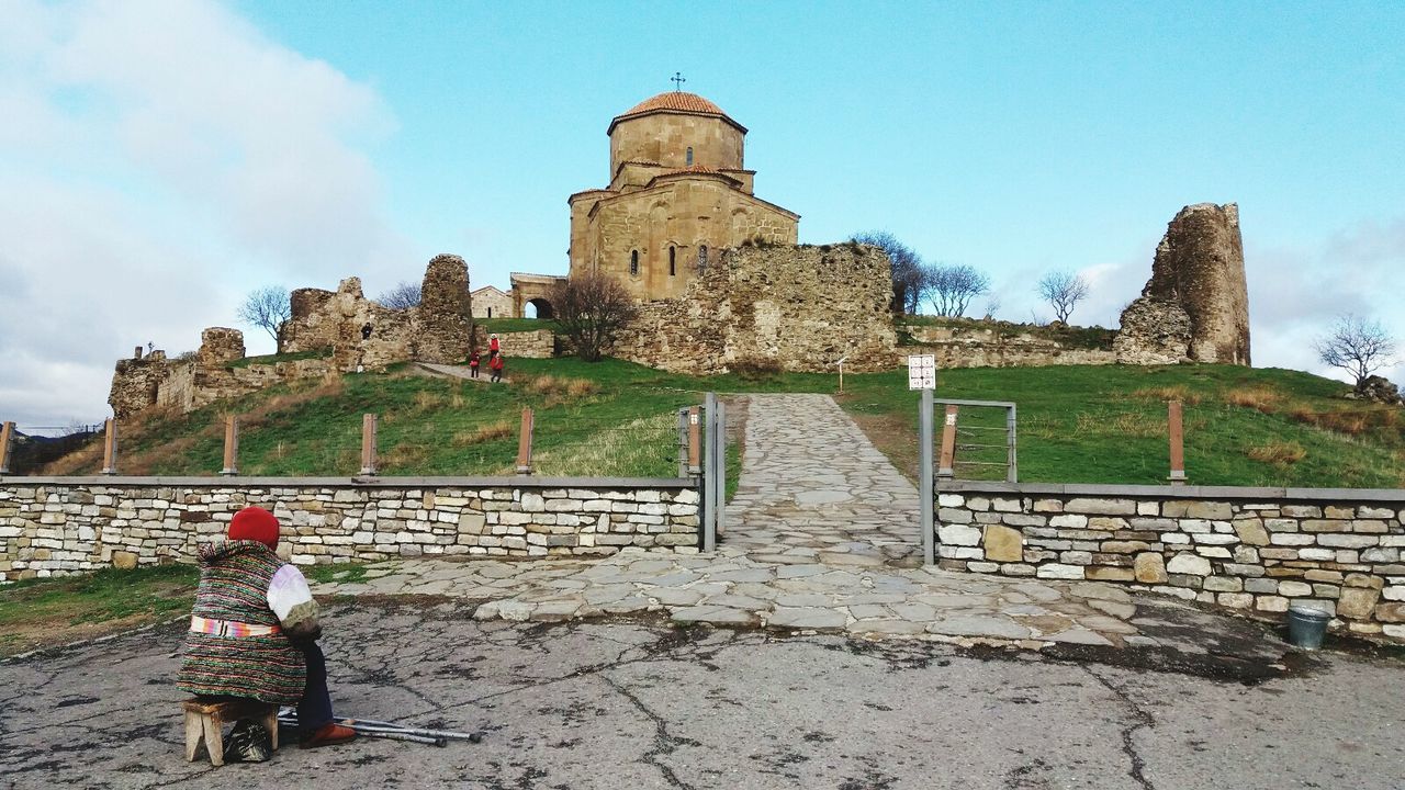 architecture, real people, built structure, one person, history, day, rear view, sky, building exterior, outdoors, old ruin, women, travel destinations, full length, ancient civilization, adult, people