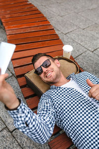 Midsection of man holding mobile phone while sitting outdoors