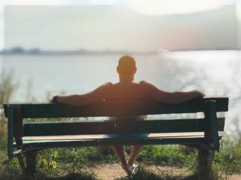 Rear view of man sitting on bench in park