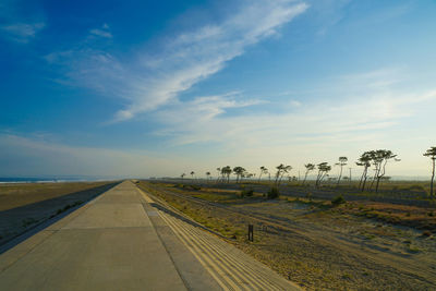 Road amidst field against sky