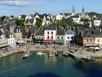 Sailboats moored in sea by town against sky