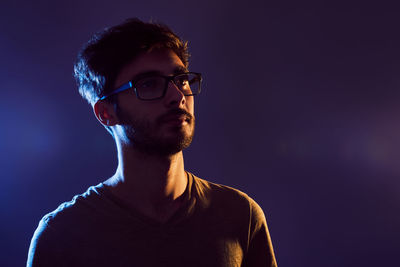 Close-up of man wearing eyeglasses against gray background