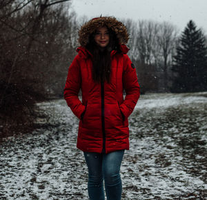 Portrait of young woman standing on snow covered land