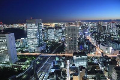 High angle view of illuminated street amidst buildings in city at night