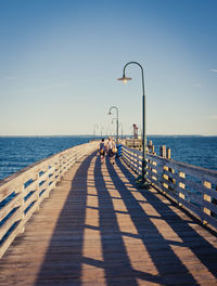 Rear view of couple walking on wooden pier