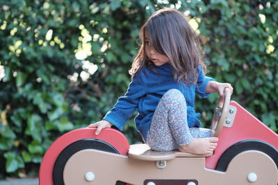 Girl looking away while sitting on spring ride at park