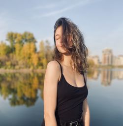 Beautiful woman standing by lake against sky