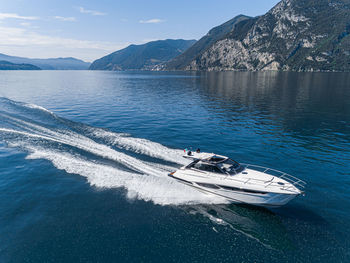 Boat sailing in sea against mountains