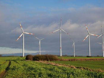 Windmills on field against sky