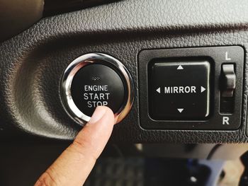 Close-up of hand pushing start button in car