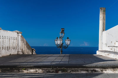 Built structure by sea against clear blue sky