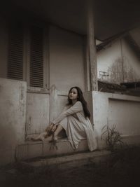 Full length portrait of woman sitting at home