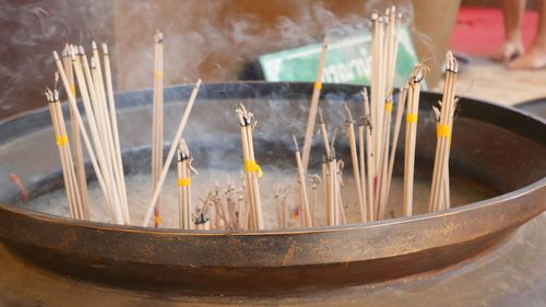 Close-up of incense sticks burning in container