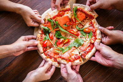 Close-up of people holding pizza served on table