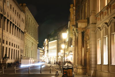 Illuminated street amidst buildings at night