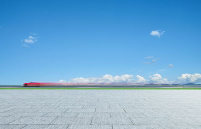 Blurred motion of car moving on road against blue sky during sunny day