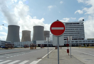 Road sign in city against sky