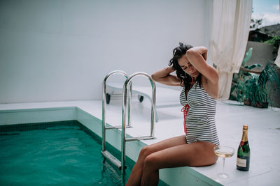 Midsection of woman sitting by swimming pool