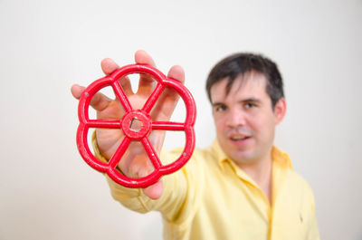 Portrait of mid adult man holding floral pattern metal against gray background