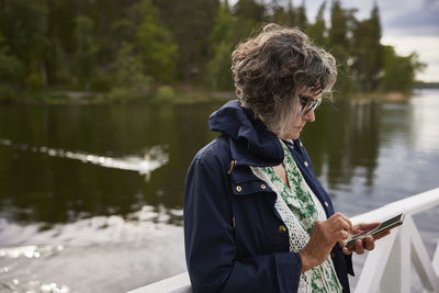 Woman using cell phone at lake