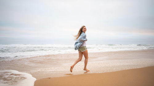 Full length of woman standing at beach against sky