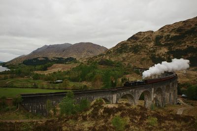 Scenic view of steam train and mountains against sky