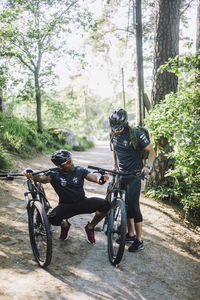 Man talking to male friend while crouching between cycles on footpath