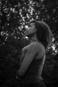 Side view of thoughtful young woman against trees