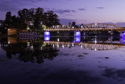 Illuminated bridge over river against sky at night