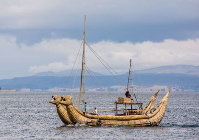 Fishing boat sailing in sea against sky