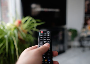 A man is holding a tv remote while selecting a program on the flat screen tv in the living room