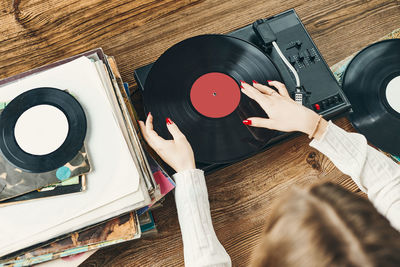 Young woman listening to music from vinyl record player. playing music on turntable player. vintage