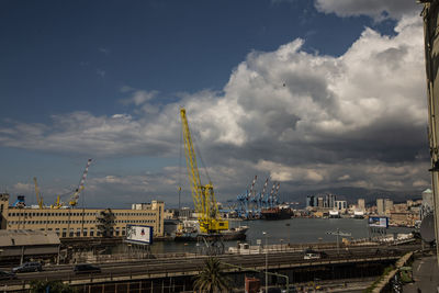 Cranes at harbor against sky in city