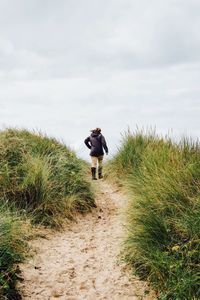 Man walking on grass against sky