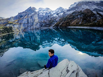 Man sitting in lake against mountains