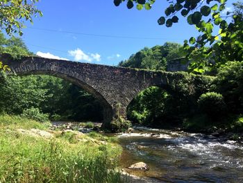 Low angle view of arch bridge over river against sky