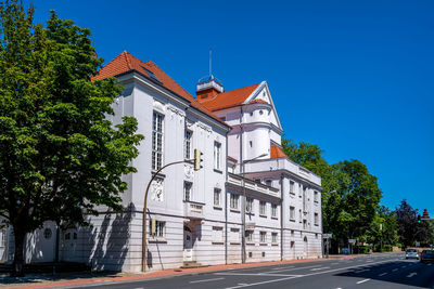 Road amidst buildings against clear blue sky