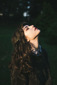 Young woman looking up while standing on field