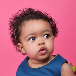 Close-up of baby girl against pink wall